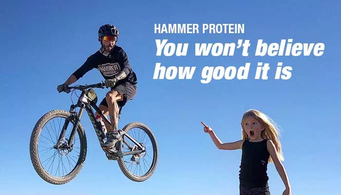 Mountainbike-os ugratás közben a levegőben, mellette egy kislány csodálkozva mutat rá, a kép felirata Hammer Protein