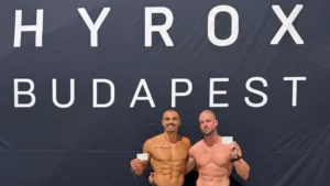Két versenyző a HYROX Budapest felirata előtt a verseny után