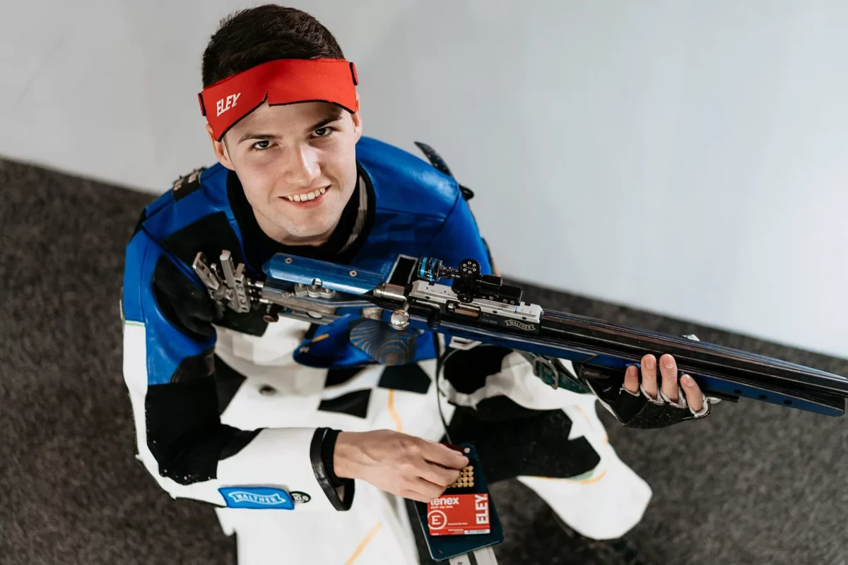 Péni István sportlövő versenymezben mosolyogva pózol a légpuskájával
